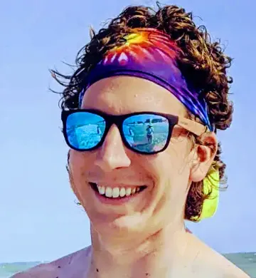 a headshot of Ben at the beach with a big smile on his face